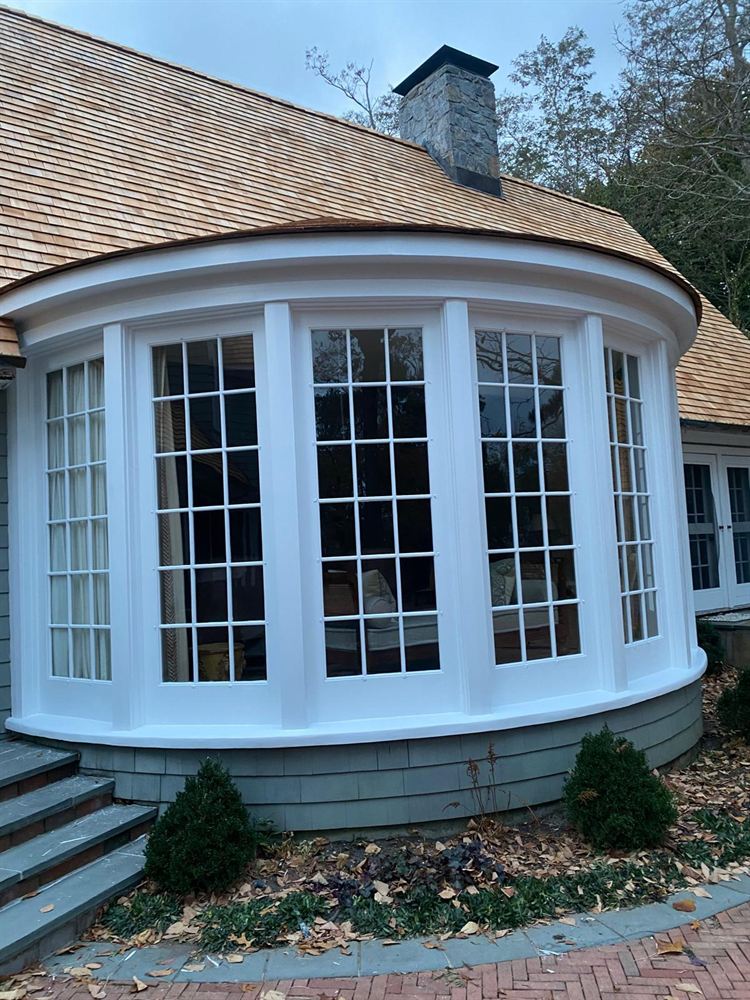 Finished exterior painting of a curved bay window under a cedar roof in the Hamptons