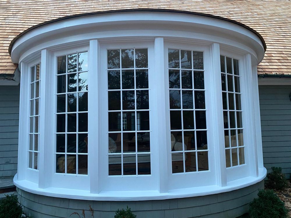 Curved bay window with freshly painted white trim after exterior painting in the Hamptons