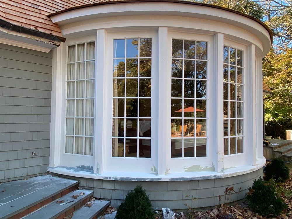 Curved bay window with patched, primed sills before exterior painting in the Hamptons