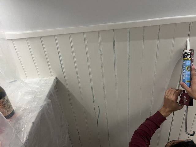 Painter caulking beadboard seams before priming and painting