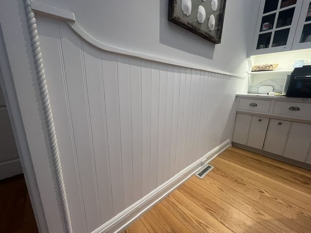 Freshly painted beadboard wainscoting leading into a kitchen in a Hamptons home