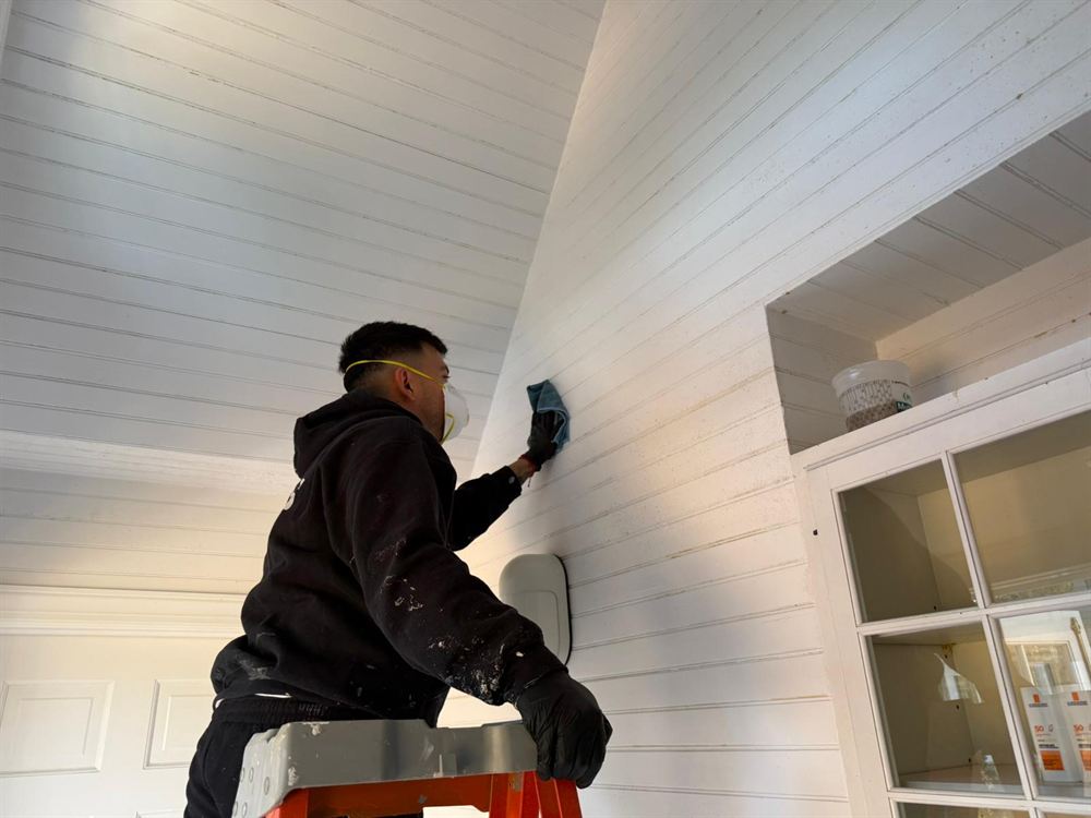 Painter washing a beadboard ceiling before painting
