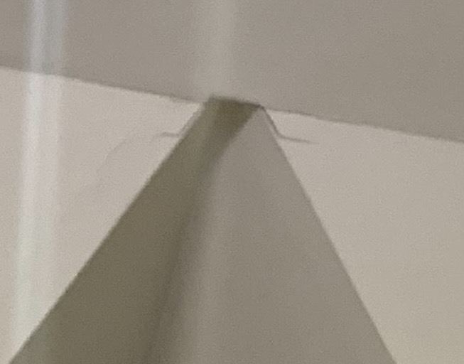 Cracked drywall seam where two ceiling planes meet before repair
