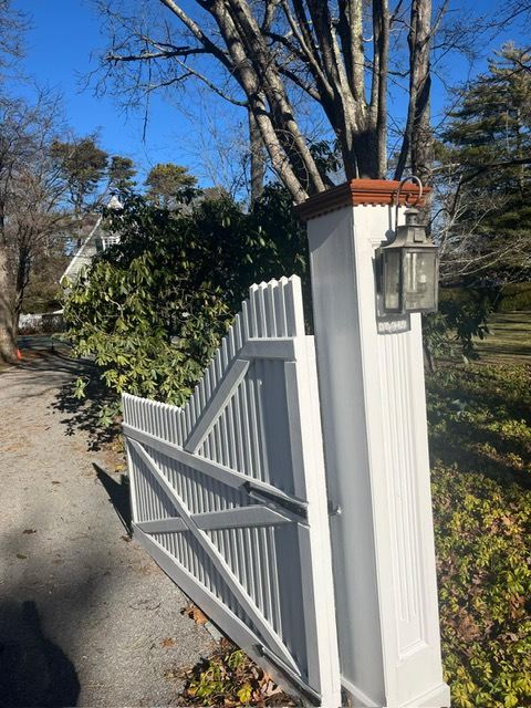 Painted white entry column with lantern and wooden driveway gate