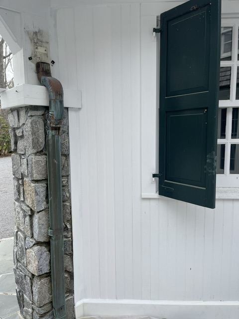 Repaired and repainted white beadboard entry wall with dark green shutters