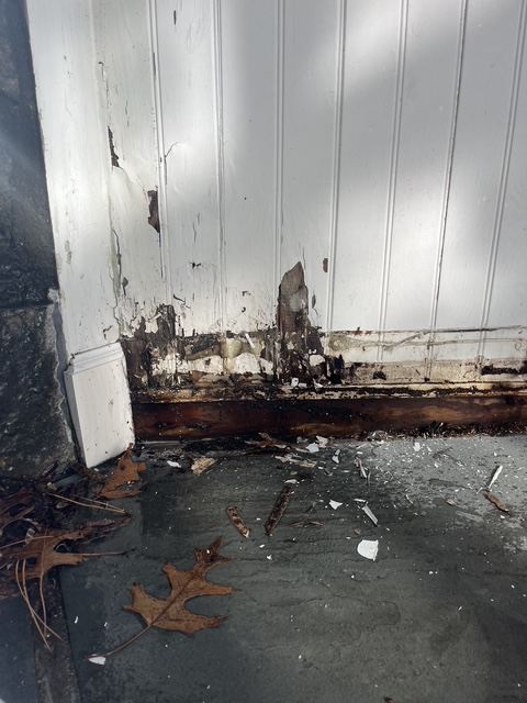 Rotted wood base trim on an exterior beadboard entry wall before repair