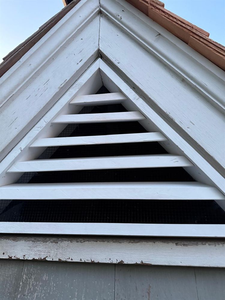 Weathered triangular gable vent and trim before exterior painting