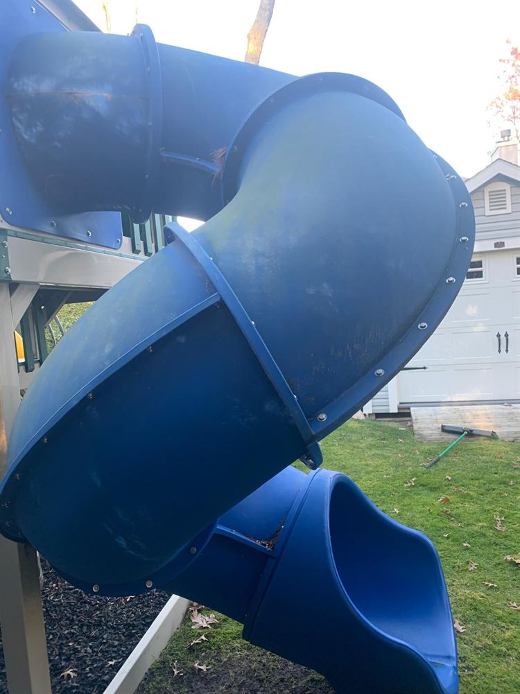 Dirty blue tube slide streaked with mildew before power washing