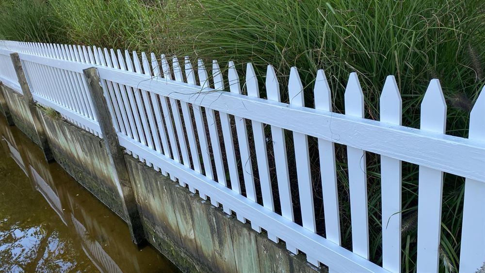 White painted picket fence along a Hamptons waterfront after painting
