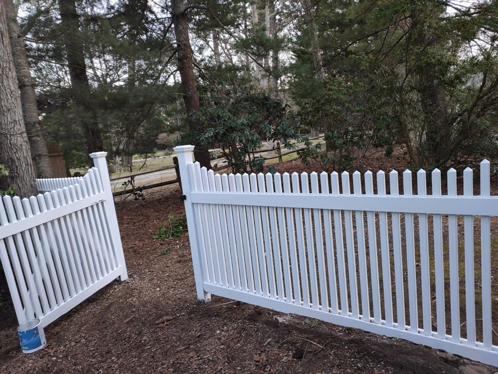 Freshly painted white picket fence in a wooded Hamptons yard